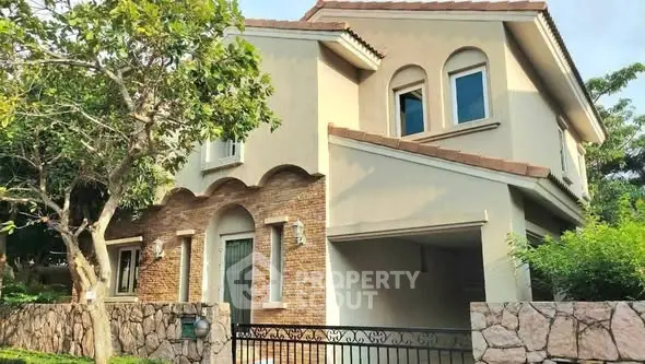 Charming two-story house with rustic brick facade and lush greenery.