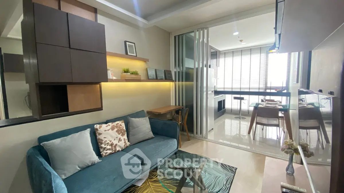 Modern living room with stylish decor and glass partition leading to dining area.