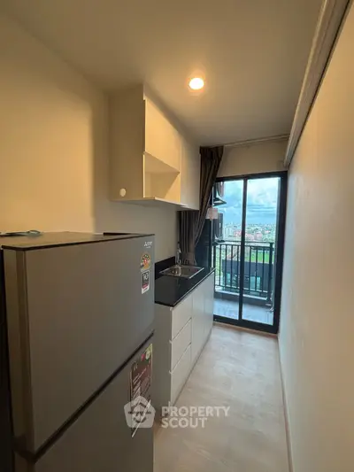 Compact kitchen with balcony view in modern apartment