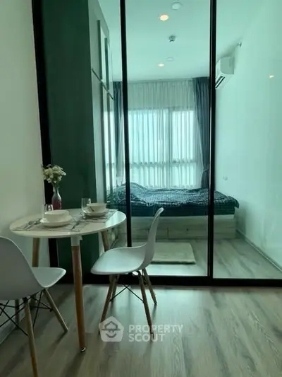 Modern studio apartment with glass partition and cozy dining area.