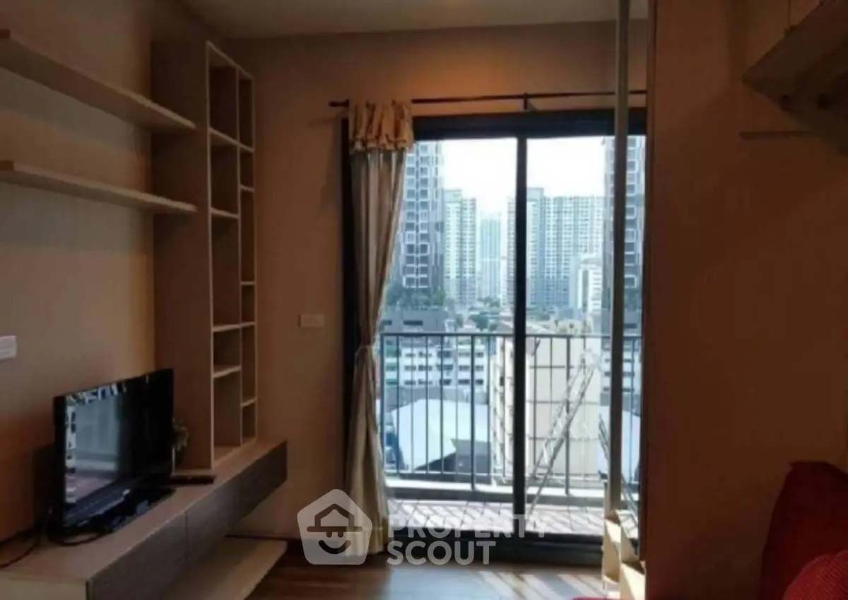 Modern living room with balcony view of city skyline, featuring built-in shelves and cozy ambiance.