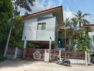 Modern two-story house with lush greenery and a motorbike parked in front.
