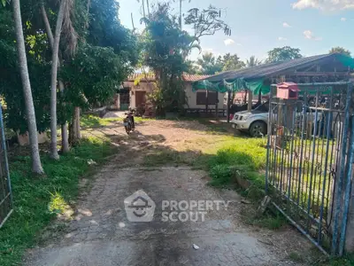 Charming rural property with spacious yard and gated entrance, featuring lush greenery and ample parking space.