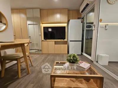 Modern living room with wooden furniture and sleek kitchen appliances in a cozy apartment.