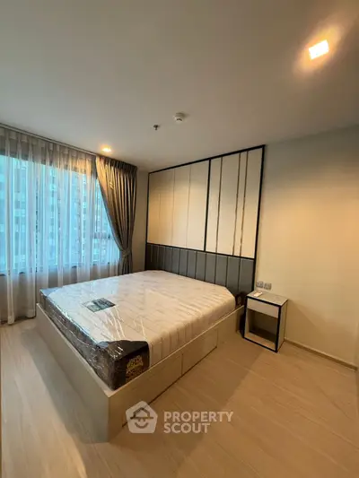 Modern bedroom with large window and stylish decor in a high-rise apartment.