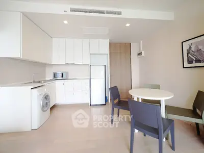 Modern kitchen with white cabinets, washing machine, and dining area in a stylish apartment.