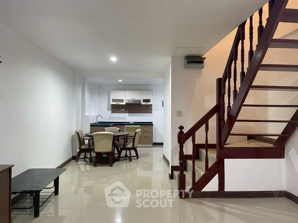 Spacious open-plan living area with modern kitchen and elegant wooden staircase.
