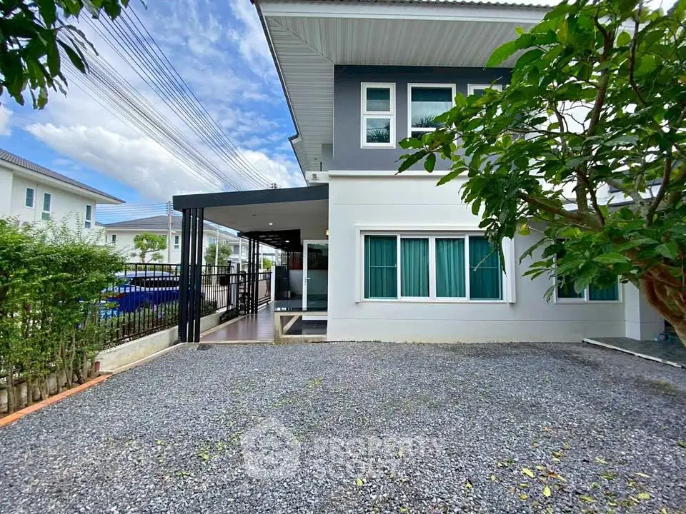 Modern two-story house with spacious gravel driveway and lush greenery.