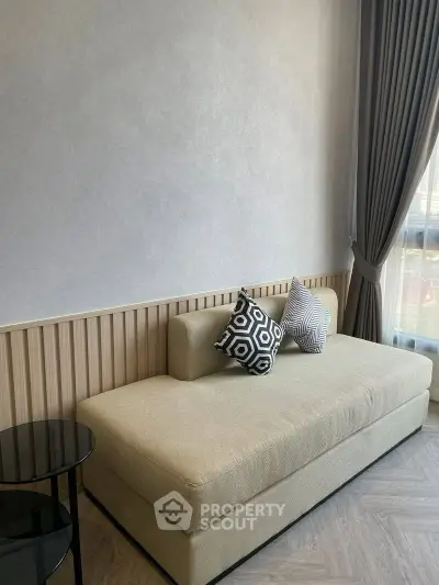 Modern living room with stylish sofa and geometric cushions, featuring elegant curtains and natural light.