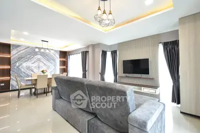 Modern living room with stylish decor and open dining area, featuring sleek furniture and elegant lighting.
