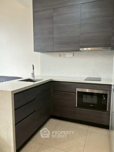 Modern kitchen with sleek dark cabinetry and built-in microwave