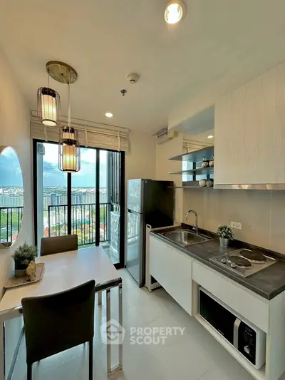 Modern kitchen with balcony view, sleek appliances, and stylish dining area in a high-rise apartment.