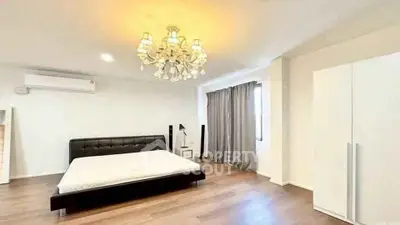Spacious bedroom with elegant chandelier and modern furnishings in a stylish apartment.