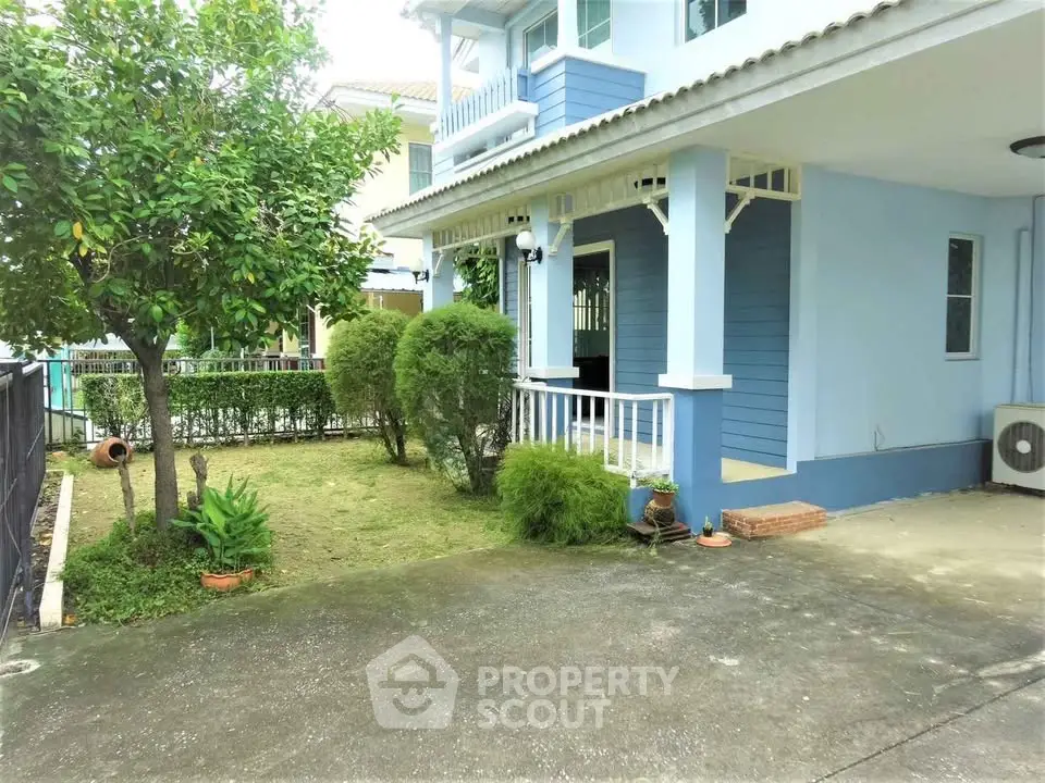 Charming blue house with lush garden and spacious driveway in serene neighborhood.