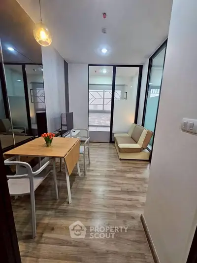 Modern living room with stylish decor and wooden flooring, featuring a cozy seating area and elegant lighting.