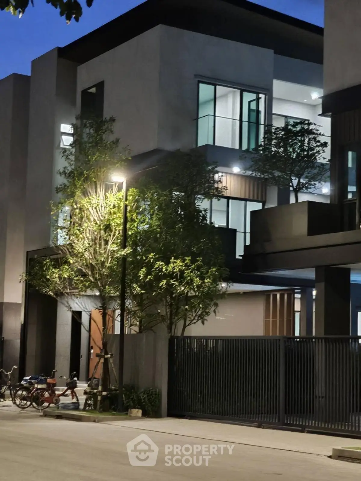 Modern architectural building with sleek design and lush greenery at twilight.