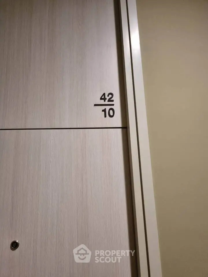 Modern apartment door with unit number 42/10, featuring sleek design and neutral tones.