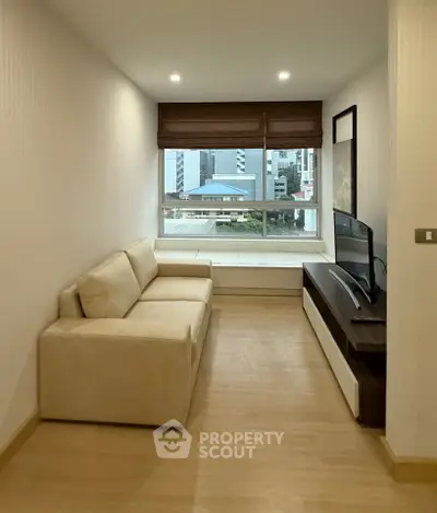 Cozy living room with a city view, featuring a comfortable sofa and modern TV setup.