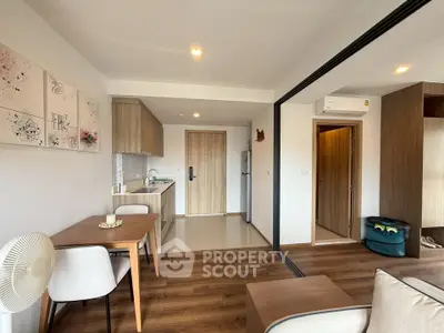 Modern open-plan living room with kitchen, wooden flooring, and stylish decor in a cozy apartment.