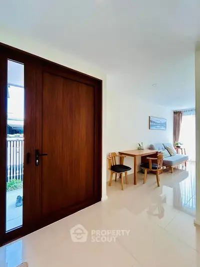 Modern living room with wooden door and elegant dining area, featuring natural light and stylish decor.