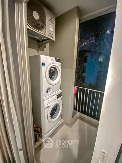 Compact laundry area with stacked washer and dryer in modern apartment balcony.