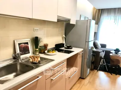 Modern kitchen with sleek cabinetry and cozy living area in open layout apartment.