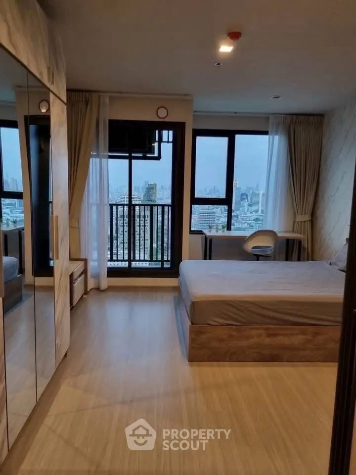 Modern bedroom with city view and large windows in a high-rise apartment.