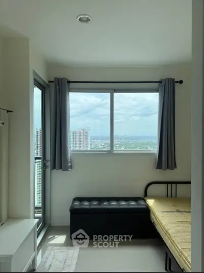 Bright bedroom with large window offering stunning city view and modern minimalist decor.