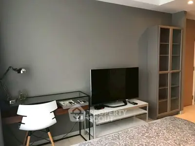 Modern bedroom with sleek desk, TV, and stylish storage cabinet