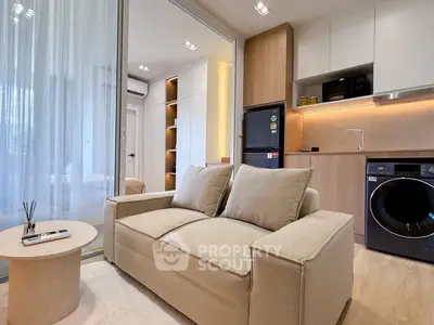 Modern living room with cozy sofa, sleek kitchen, and integrated appliances in a stylish apartment.