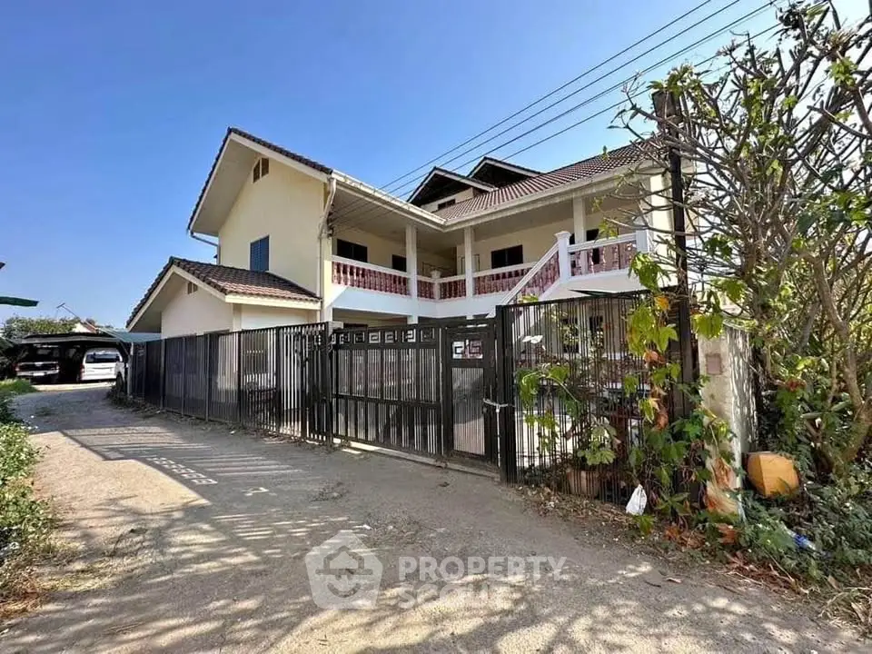 Spacious two-story house with gated entrance and lush greenery