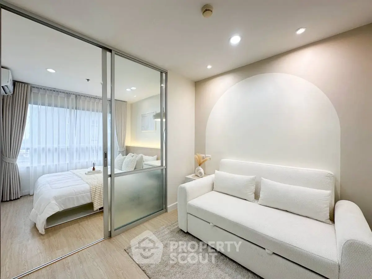 Modern studio apartment with cozy living area and bedroom separated by glass partition.