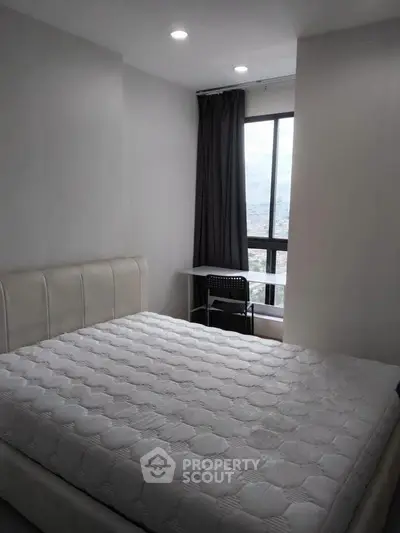 Modern bedroom with large window and city view, featuring a comfortable bed and study desk.