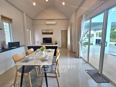 Spacious open-plan living and dining area with modern decor and large windows leading to outdoor patio.