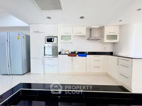 Spacious modern kitchen with sleek white cabinetry and built-in appliances.