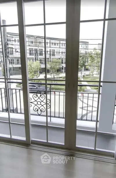 Spacious balcony with elegant railing overlooking modern townhouses and lush greenery.