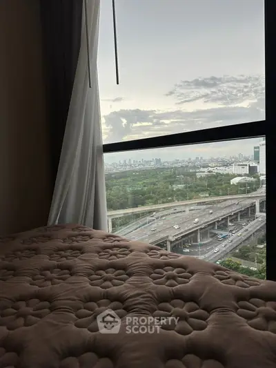 Stunning cityscape view from a cozy bedroom window, showcasing urban skyline and highway.