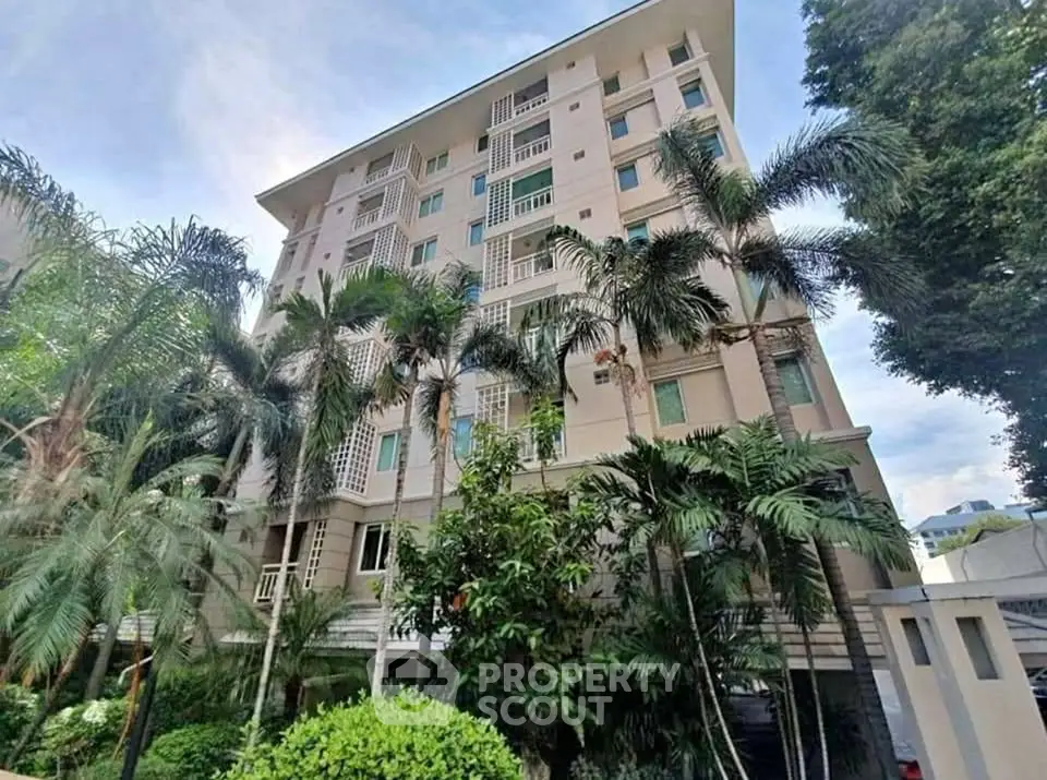 Elegant residential building surrounded by lush greenery and palm trees.