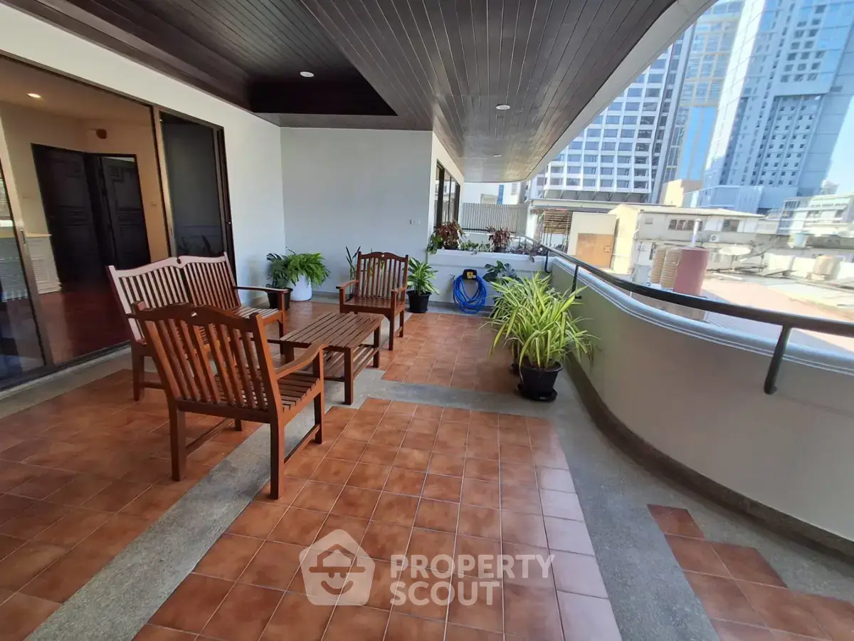 Spacious balcony with wooden furniture and city view, perfect for relaxation and entertaining guests.