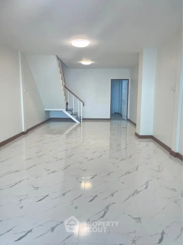 Spacious open-plan living area with elegant marble flooring and modern staircase.