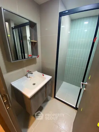 Modern bathroom with sleek sink and glass shower enclosure in contemporary apartment.
