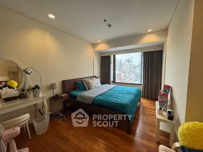 Spacious bedroom with city view, wooden flooring, and modern decor in high-rise apartment.