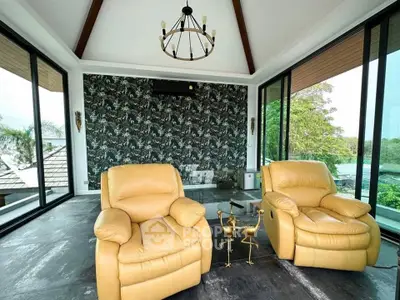Luxurious living room with panoramic windows and elegant decor, featuring plush leather armchairs and stylish lighting.