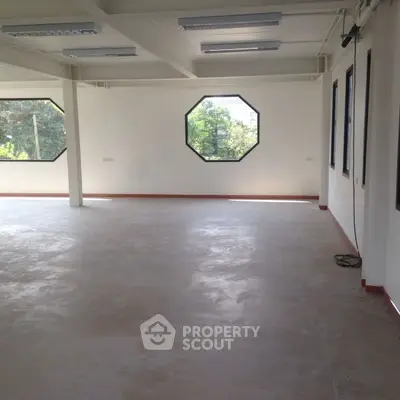 Spacious open-plan room with large windows and natural light, ideal for office or studio space.