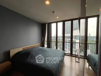Modern bedroom with large windows offering city views in a stylish apartment.