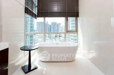 Luxurious bathroom with city view and modern freestanding bathtub in high-rise apartment.