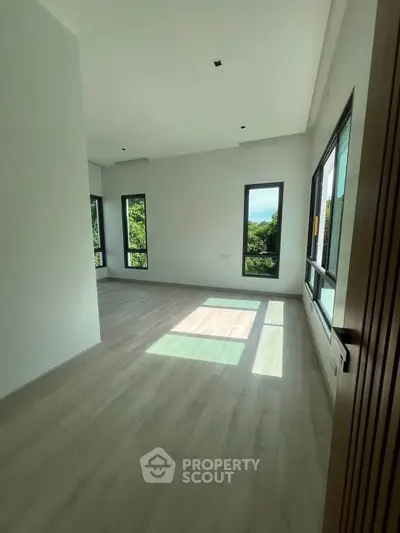 Spacious room with large windows offering lush green views, perfect for a serene living experience.