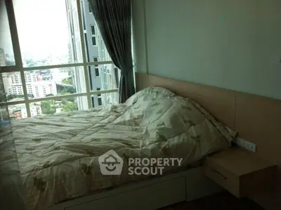 Modern bedroom with large windows offering stunning city views in a high-rise apartment.