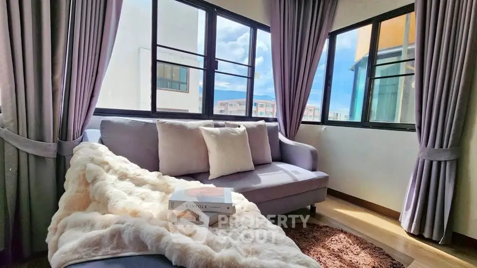 Cozy living room with plush sofa and large windows offering scenic views.