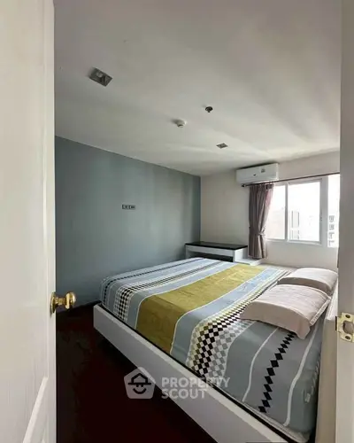 Cozy bedroom with modern decor and ample natural light from large window.
